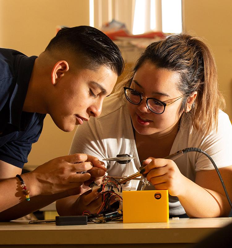 2 electrical engineering students working on circuit board